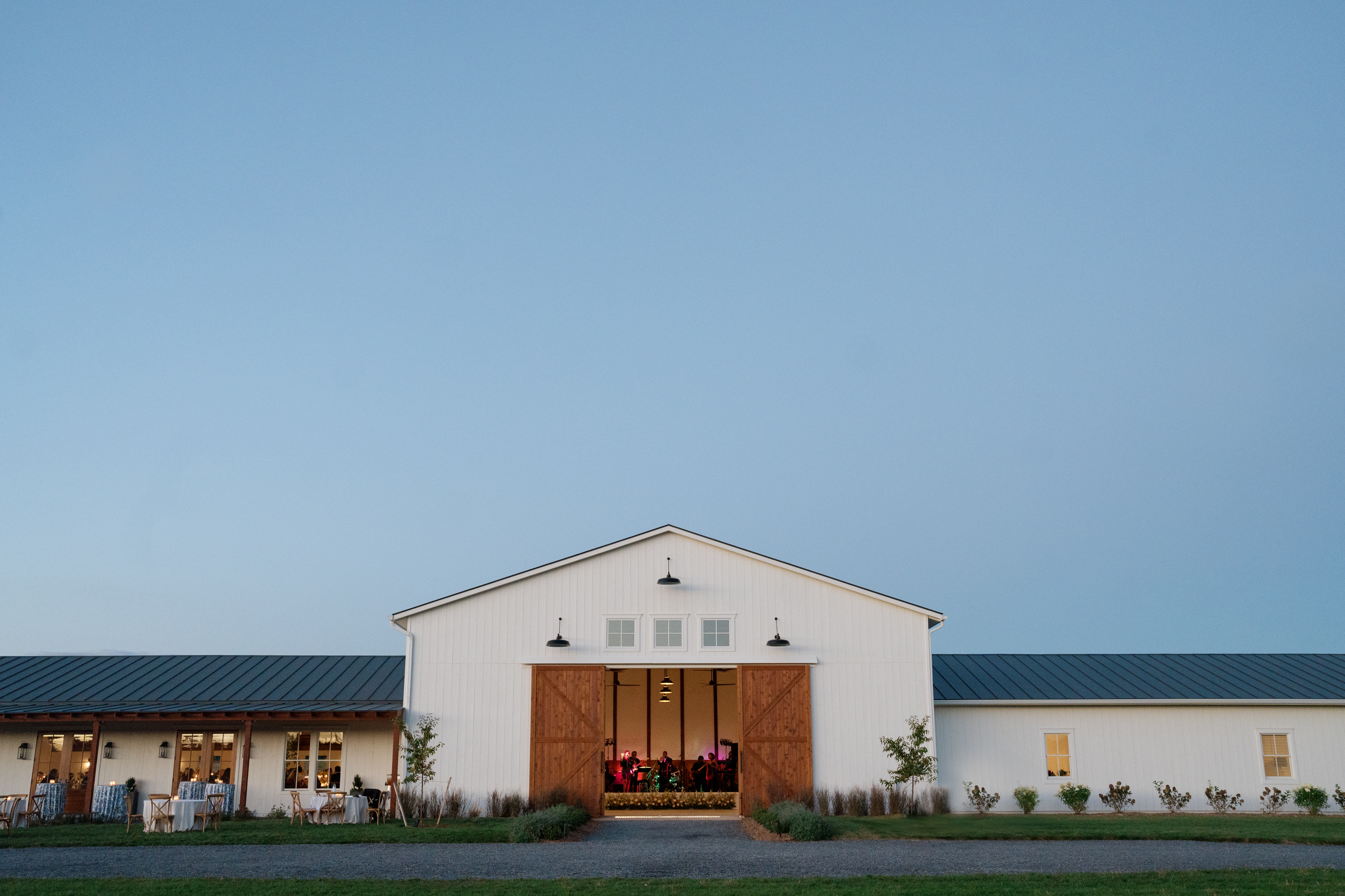 The Barn at dusk under a clear sky, its big doors open with the band playing inside