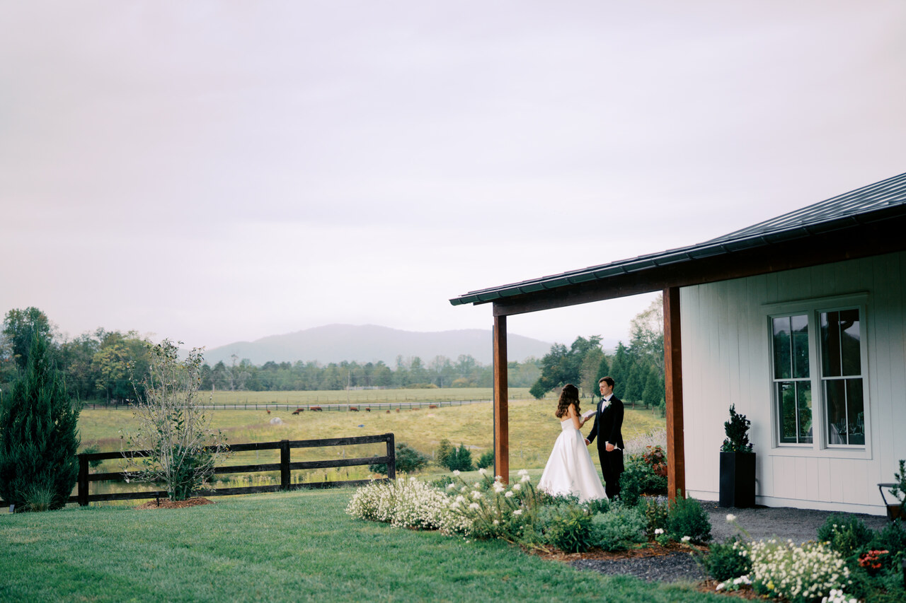 A couple on the North Hall veranda with pasture and the Blue Ridge beyond